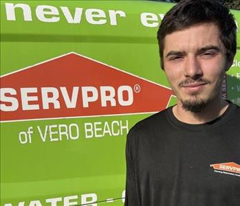 Headshot of employee in black shirt in front of green background