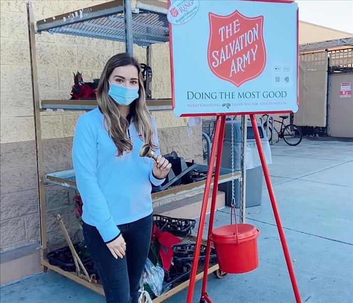 girl ringing bell in front of The Salvation Army sign