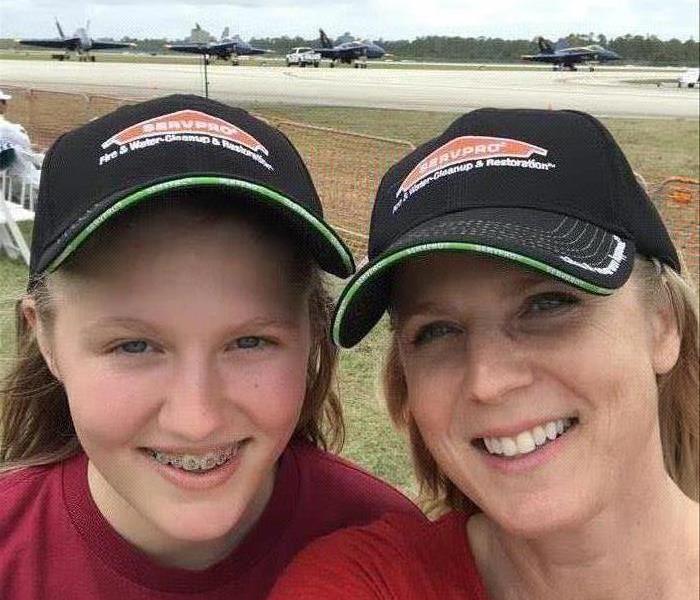 A mom and daughter taking a selfie wearing SERVPRO hats