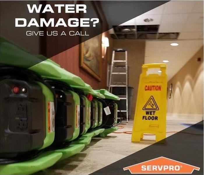 Air movers lined up in a hallway with the words “Water Damage? Give us a call.”