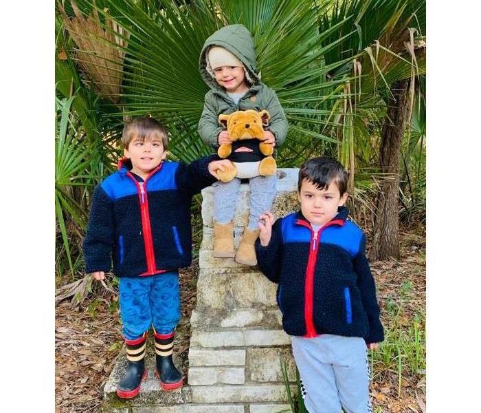 Three toddlers standing next to a stone monument 