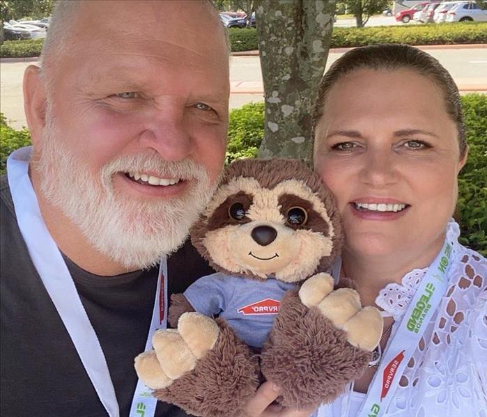 man and woman holding sloth stuffed animal