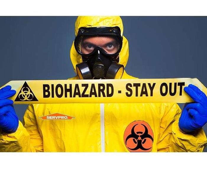man in yellow tyvek suit holding biohazard tape