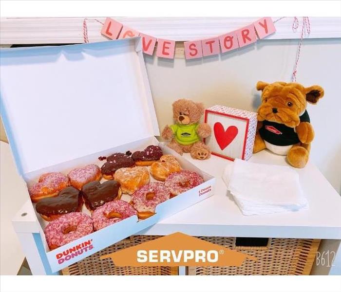 Bulldog Plushie in SERVPRO shirt next to a box of heart shaped donuts