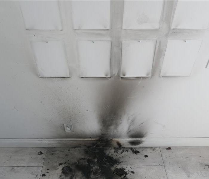 White wall covered in black soot from a car battery explosion. 