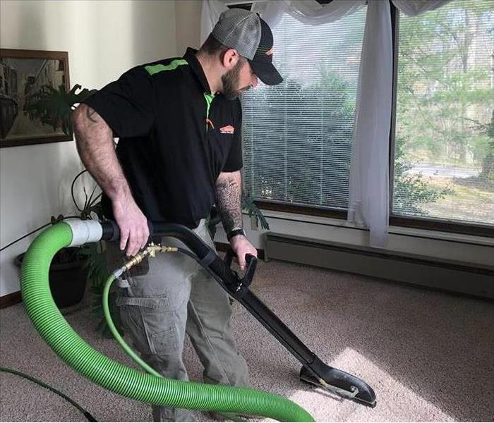 Man in SERVPRO uniform carpet cleaning in a bedroom
