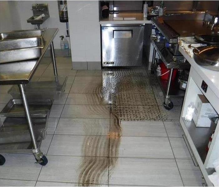 Restaurant kitchen with partially cleaned floors.