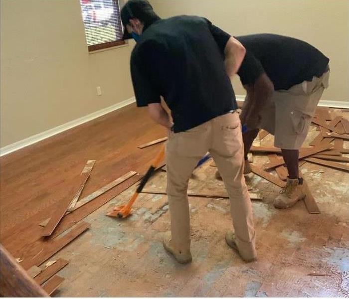 Two SERVPRO technicians tearing out water damaged wood flooring