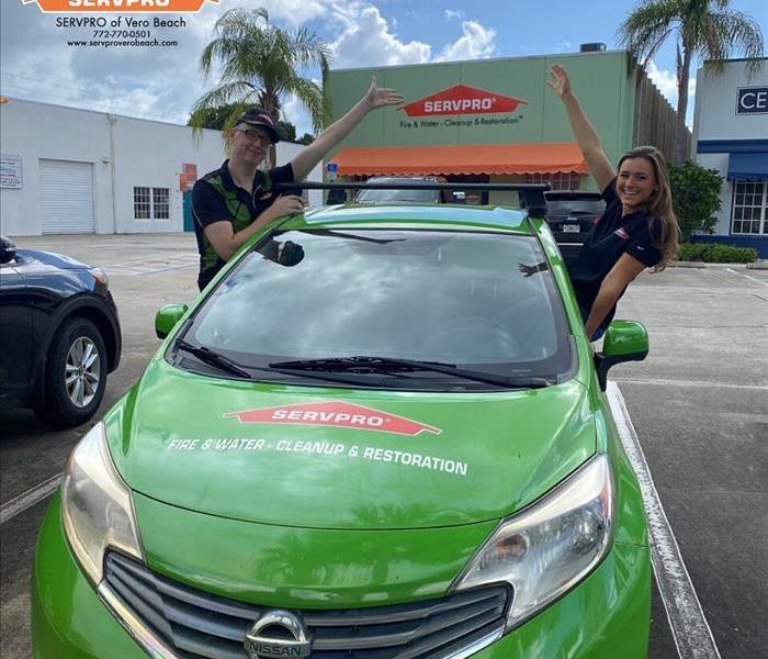 Man and Woman Posing out of car window to showcasing SERVPRO of Vero Beach’s store front
