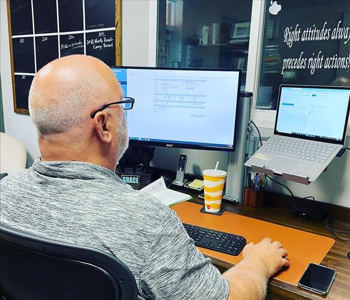 Man sitting at computer working on an insurance claim for water loss.