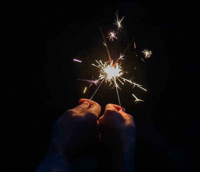 A man holding up a sparkler in each hand. 