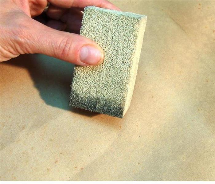 Dry sponge being used to remove soot from surface