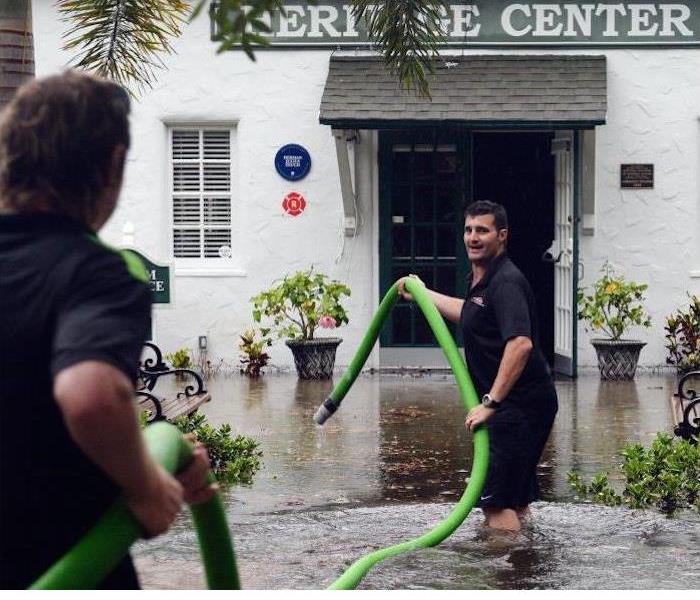 Two men getting ready to pump out water from a flooded building