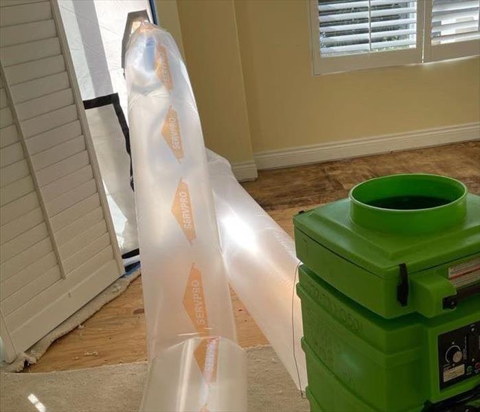 Servpro airscrubber with plastic tubing connected, set up for negative air filtration.